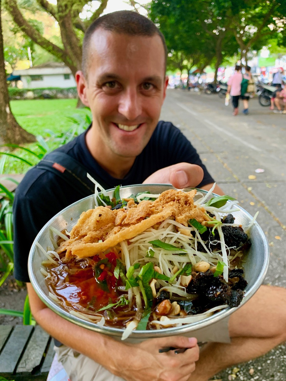 In this photo provided to Tuoi Tre News, Thomas Southam is posing with his dish of 'goi du du kho bo' (green papaya salad topped with dried beef organ) at a park in Ho Chi Minh City.