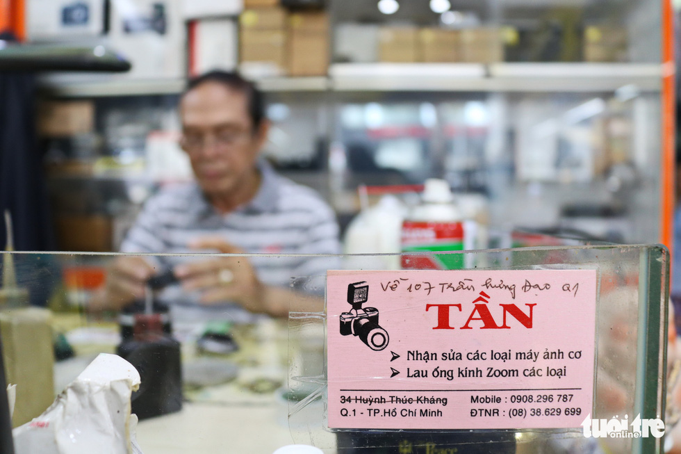 The sign of Tan’s ‘shop’ is a small name card stick at his table inside a digital camera shop in District 1. Photo: Ngoc Phuong/ Tuoi Tre