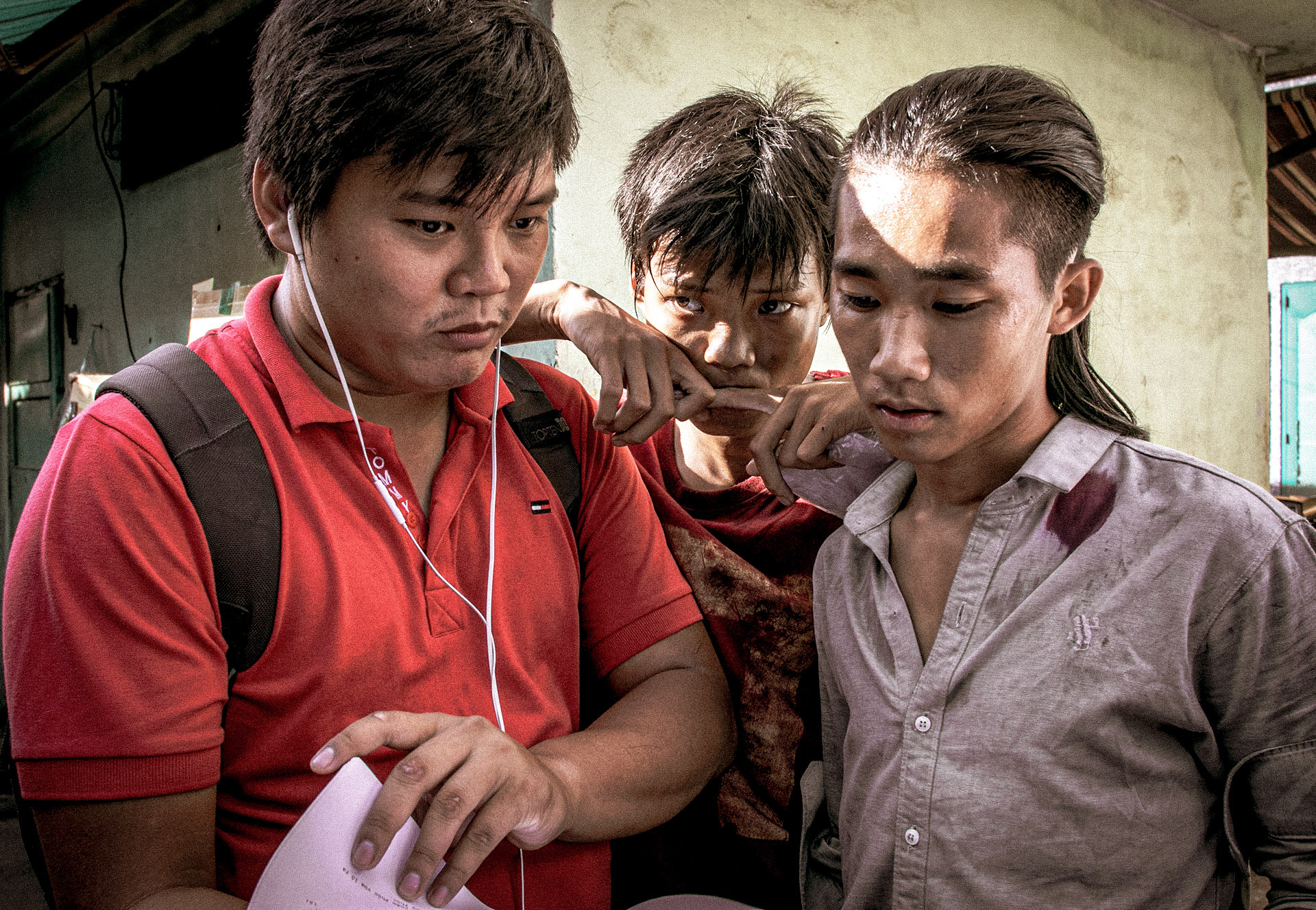 Director Tran Thanh Huy (left) wears earbuds while he stands with actors who play Rom (center) and Phuc on location in this photo supplied by CJ, the film’s distributor in Vietnam.