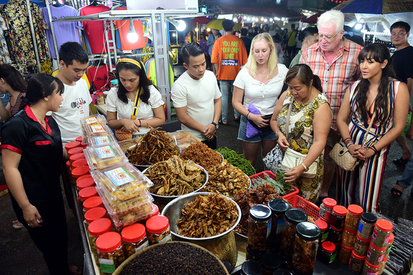Foreign visitors browse a food stall within the Phu Quoc night market on Phu Quoc Island off Kien Giang Province, Vietnam. Photo: Quang Dinh / Tuoi Tre