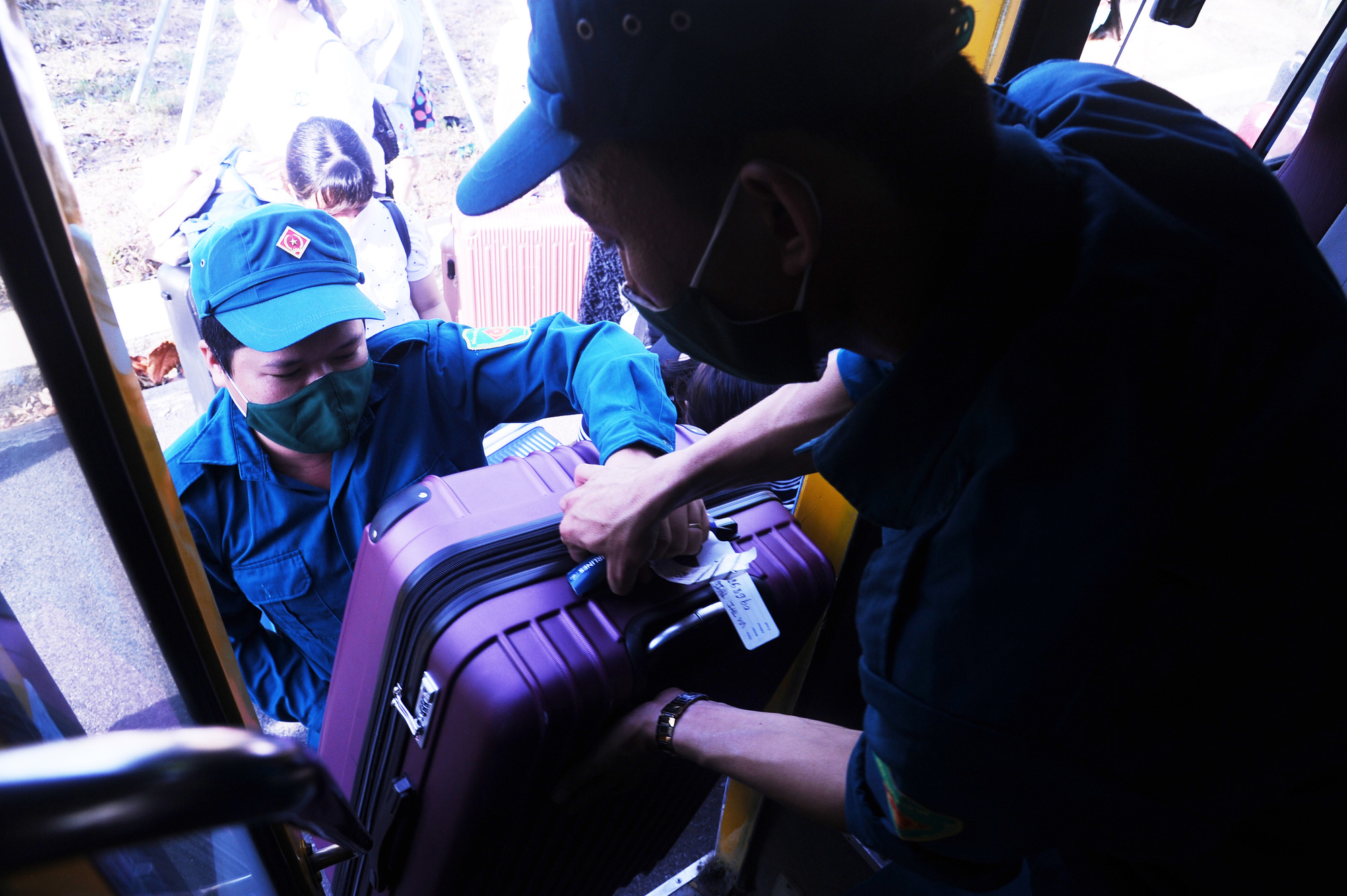 Staff members at a novel coronavirus disease (COVID-19) quarantine zone in Quang Nam Province, Vietnam help pregnant women carry their luggage onto a bus after completing their mandatory quarantine, June 12, 2020. Photo: Le Trung / Tuoi Tre