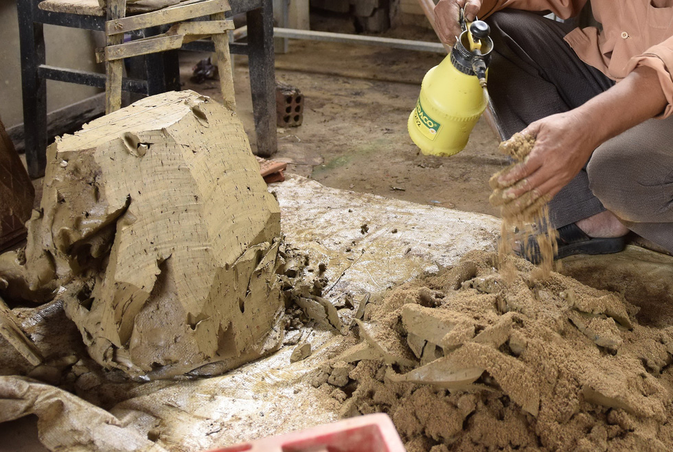 Ceramics worker spray water into the clay-sand concoction. Photo: Le Van Anh / Tuoi Tre