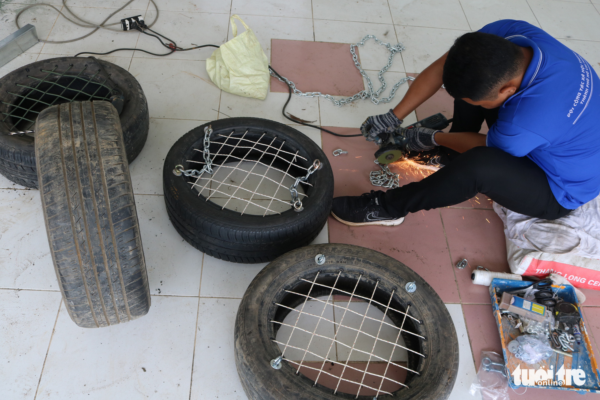 Le Quang Phu, 23, installs metal chains on old car tires to make swings for a playground in Nha Be District, Ho Chi Minh City, Vietnam. Photo: Hoang An / Tuoi Tre
