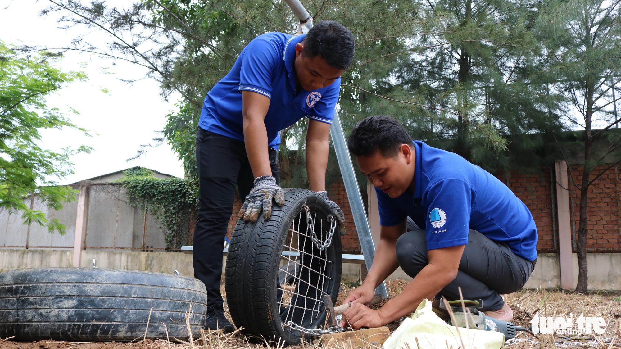 Two male volunteers are at the final stage of making an old tire swing for a playground in Nha Be District, Ho Chi Minh City, Vietnam. Photo: Hoang An / Tuoi Tre