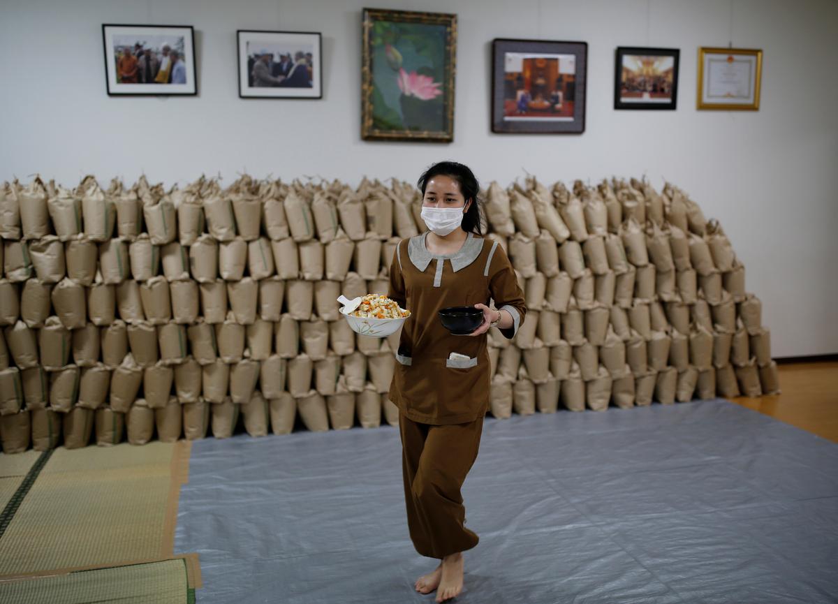 A Vietnamese migrant worker who lost her job amid the coronavirus disease (COVID-19) outbreak, walks past sacks of rice which will be sent to Vietnamese people in need and living in Japan, while she prepares for a dinner at a Buddhist temple which has turned into a shelter for young Vietnamese migrant workers in Tokyo, Japan, July 2, 2020. Photo: Reuters