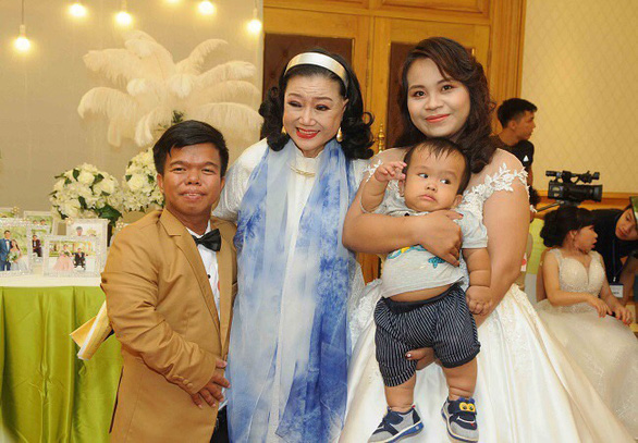 Nguyen Duy Phat and his wife, along with their baby son, are among the 40 physically challenging grooms and brides at a mass wedding organized in 2018 by Meritorious Artist Kim Cuong (center) in this supplied photo.