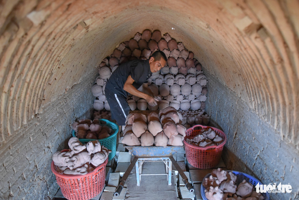 Artisan Tran Quoc Tuan puts the clay models inside the furnace in Tan Uyen Town, Binh Duong Province. Photo: Ngoc Phuong / Tuoi Tre