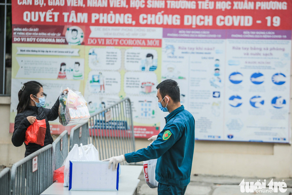 A parent sends food and necessities into the quarantine zone at Hanoi’s Xuan Phuong Primary School for her child, January 31, 2021. Photo: Nguyen Khanh / Tuoi Tre
