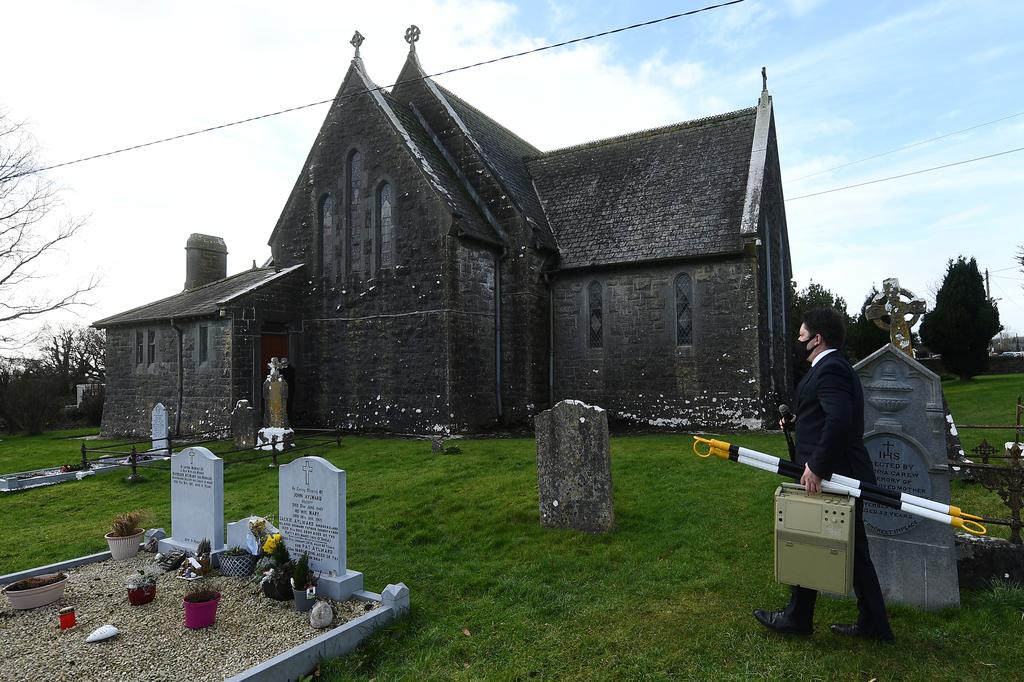 Funeral director and publican Jasper Murphy of McCarthy's Bar and Undertakers brings a speaker and microphone to the gravesite of a recently deceased local man before his funeral ceremony, amid the coronavirus disease (COVID-19) pandemic, in the County Tipperary town of Fethard, Ireland, February 3, 2021. Photo: Reuters