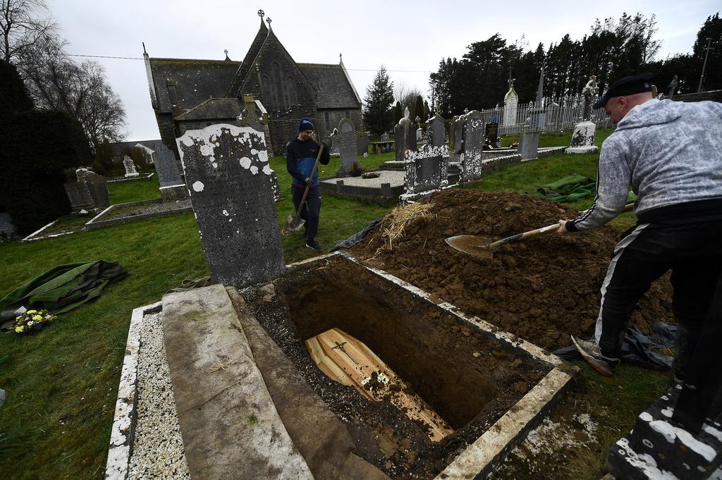 Gravedigger Lee Molony starts filling in soil over the coffin at the grave of a recently deceased local man whose funeral undertaker and publican Jasper Murphy of McCarthy's Bar directed at Fethard parish church, amid the coronavirus disease (COVID-19) pandemic, in the County Tipperary town of Fethard, Ireland, February 3, 2021. Photo: Reuters