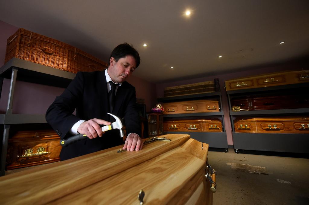 Funeral director and publican Jasper Murphy of McCarthy's Bar and Undertakers prepares a coffin by hammering the crucifix into it before collecting the body of a deceased local man from hospital, amid the coronavirus disease (COVID-19) pandemic, in the County Tipperary town of Fethard, Ireland, January 31, 2021. Photo: Reuters