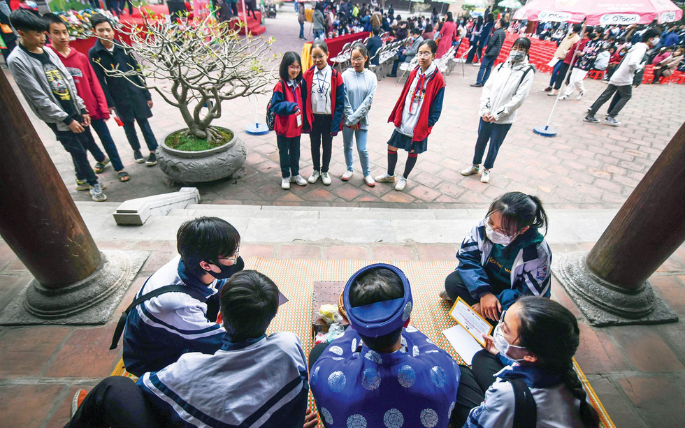 School students are enthralled as Nguyen Van Thanh demonstrates how to make to he statuettes during an extracurricular class held at Van Mieu Quoc Tu Giam (Temple of Literature), one of Hanoi’s much-loved tourist attractions. Photo: Hoang Ngoc Thach / Tuoi Tre