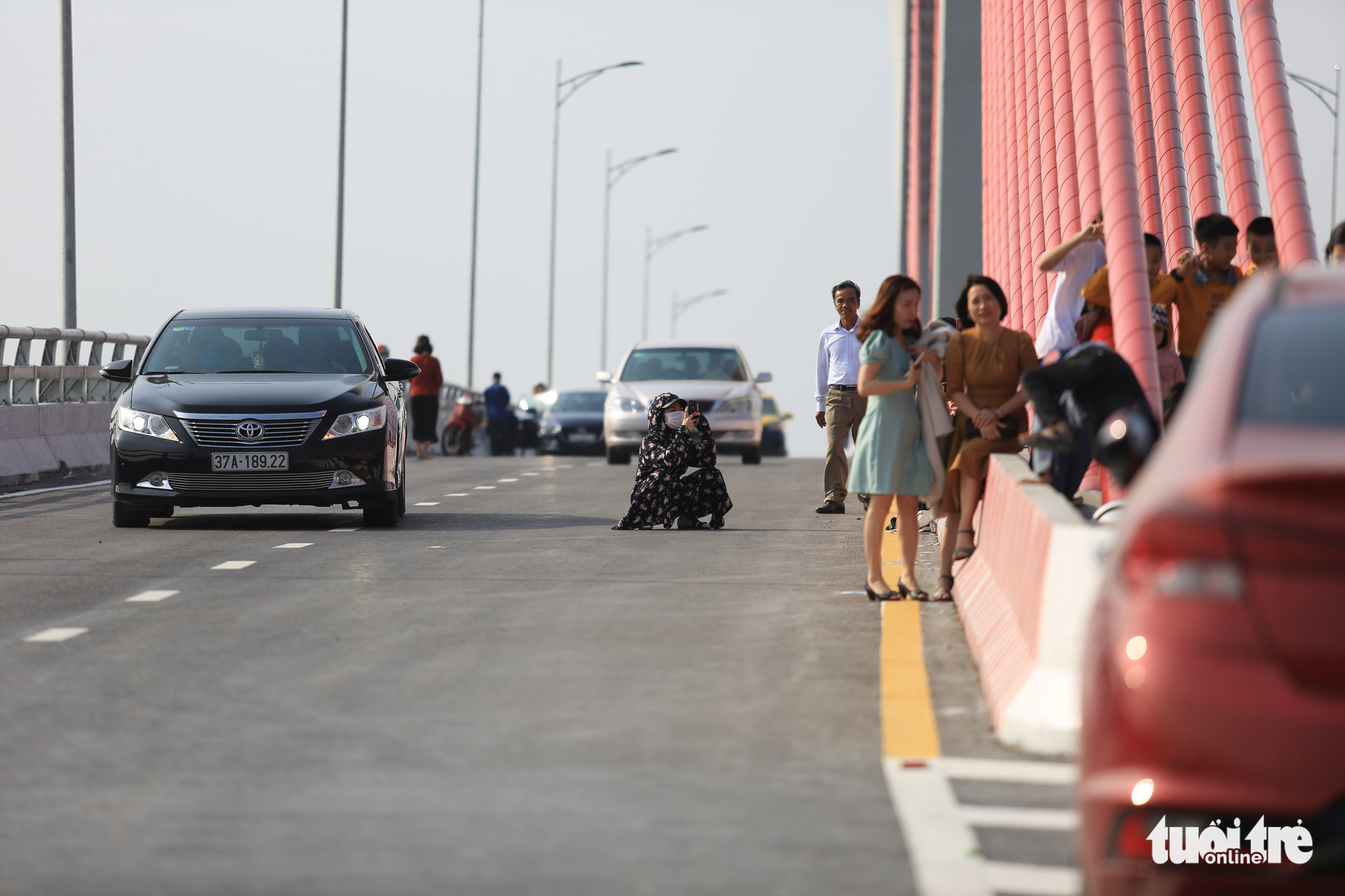 People dangerously stand and sit amidst the road on the Cua Hoi Bridge to take photos in north-central Vietnam, February 15, 2021. Photo: Ngoc Thang / Tuoi Tre