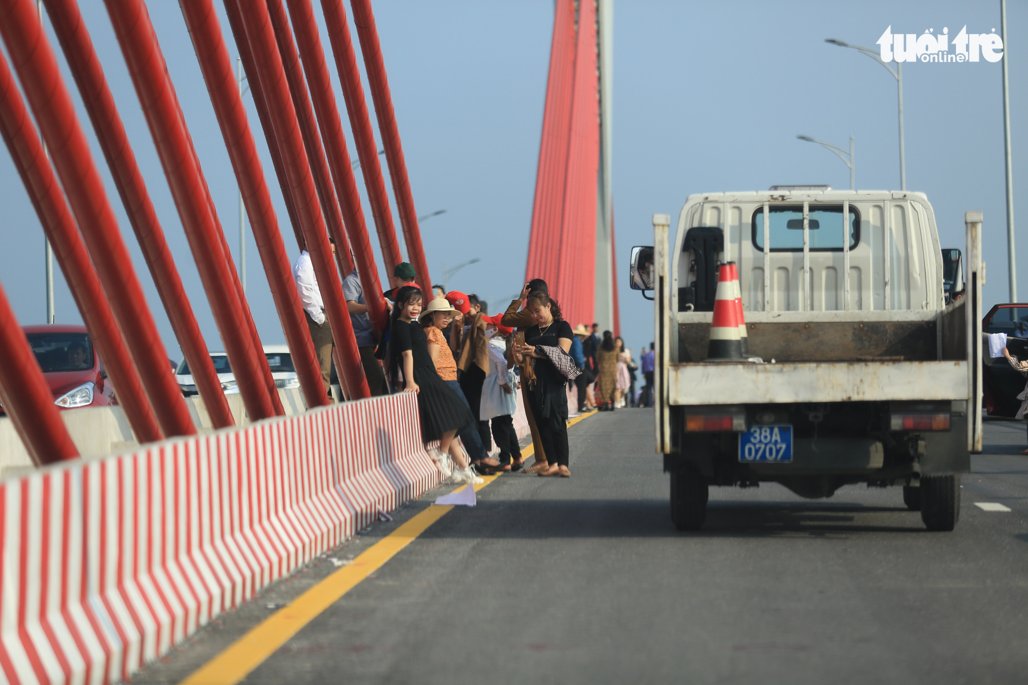 A group of people continue taking photos while traffic police officers patrol in front of them on the Cua Hoi Bridge in north-central Vietnam, February 15, 2021. Photo: Ngoc Thang / Tuoi Tre