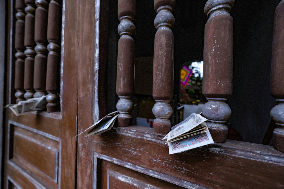 Banknotes are tucked in the gate of shuttered Quan Thanh temple in Tay Ho District, February 16, 2021. Photo: Nam Tran / Tuoi Tre