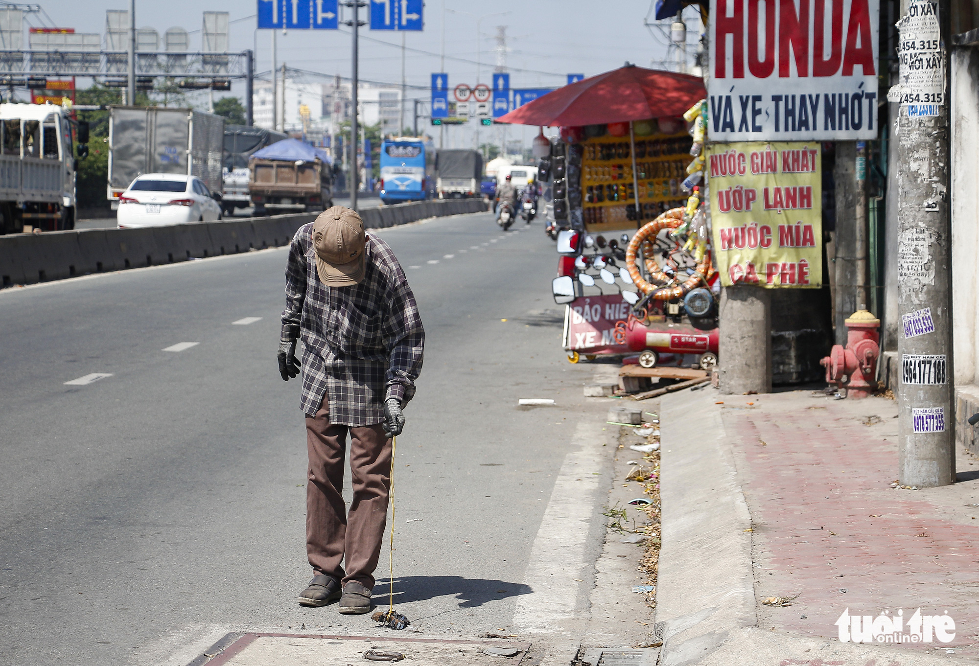 A man collects tire-puncturing nails along National Highway No.1 in Ho Chi Minh City. Photo: Chau Tuan / Tuoi Tre