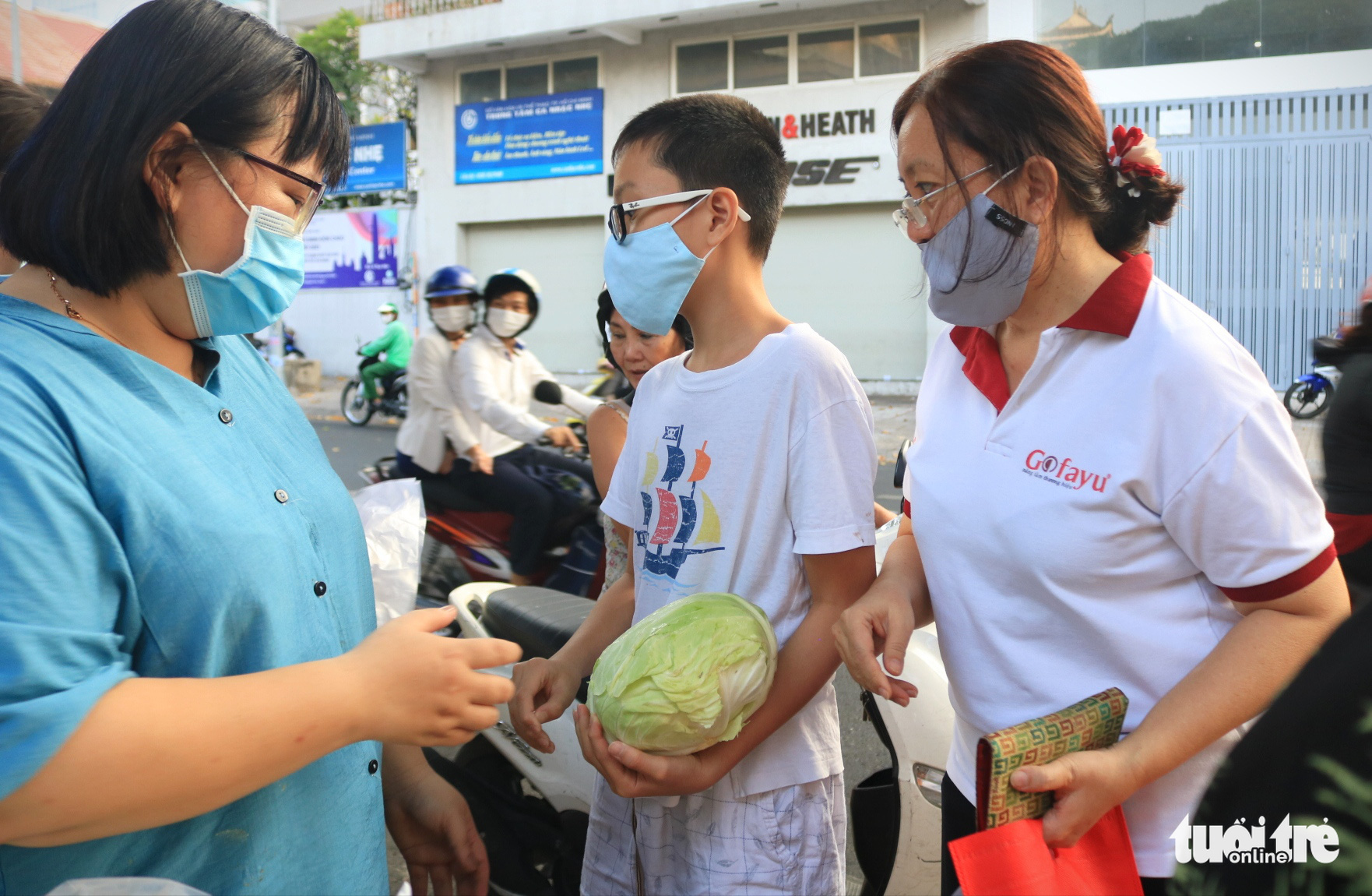 Xuan Phuc (center), a sixth grade student at Ban Co Secondary School, takes a cabbage given away from a makeshift stall in front of Phat Buu Pagoda in District 3, Ho Chi Minh City, February 23, 2021. Photo: Nhat Thinh / Tuoi Tre