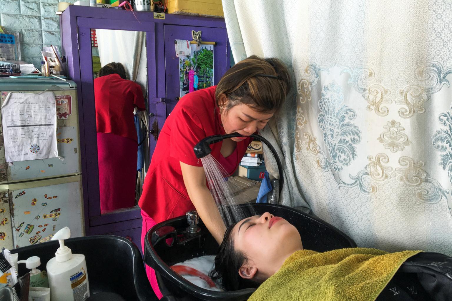 Le Thi Kim Tram holds the shower head in her mouth when washing clients' hair. Photo: Reuters