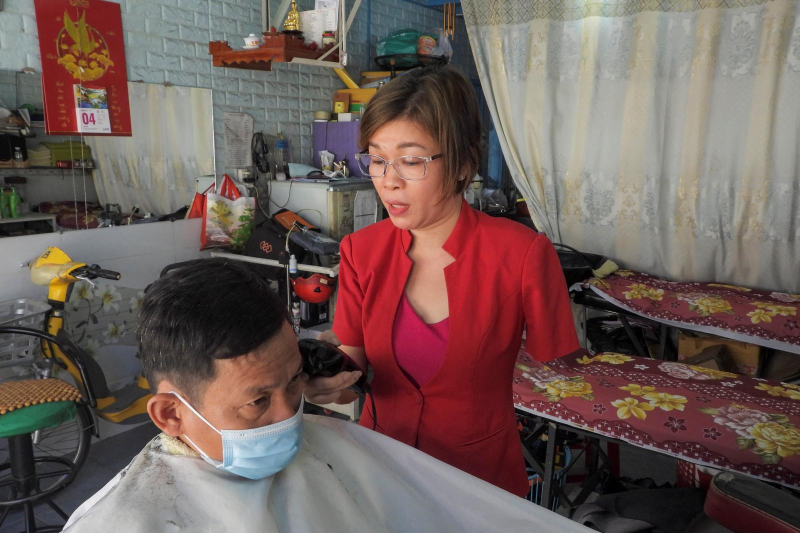 Le Thi Kim Tram, who lost her left arm in a traffic accident four years ago, works at her barbershop in Ho Chi Minh City, Vietnam March 5, 2021. Picture taken March 5, 2021. Photo: Reuters