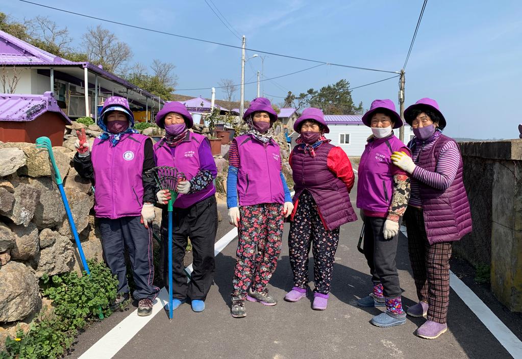 Jung Soon-shim, 88, and other residents dressed in purple clothing pose for a photograph at the Purple Island in Shinan, South Korea, March 8, 2021. Photo: Reuters