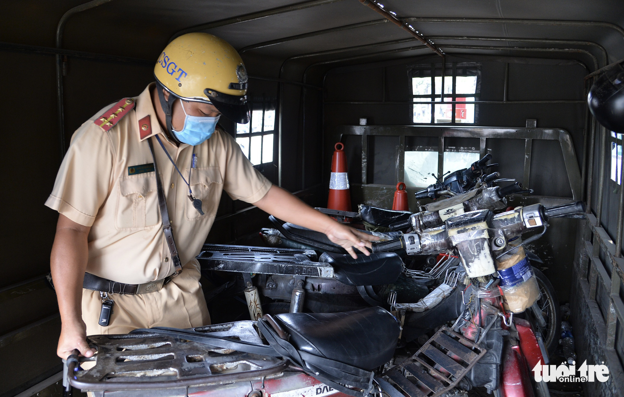 A traffic police officer seizes dilapidated motorcycles in Ho Chi Minh City, March 16, 2021. Photo: Tu Trung / Tuoi Tre